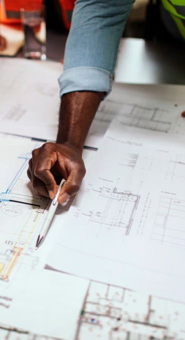 Unrecognizable architect checking drawings and plans with his colleagues